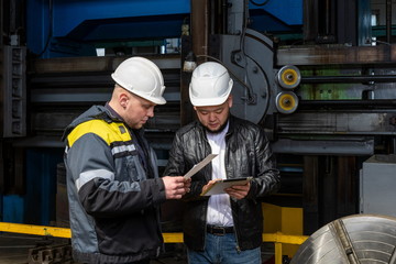 Two young engineers at a modern factory. The photo illustrates new technologies and production.