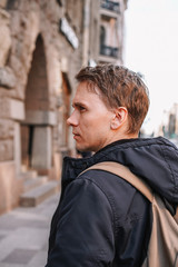 A young man in a jacket walks through the streets of the city, portrait against the background of a beautiful old building, business style