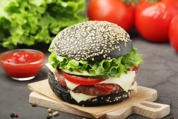 A black burger with vegetables and beef meat