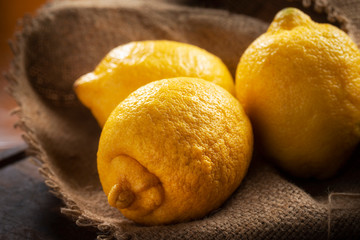 Limoni interi gialli in primo piano appoggiati su un sacco di iuta