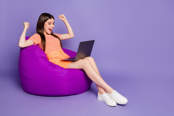 Full size profile photo of cheerful lady sit comfy beanbag look notebook got startup approve boss wear orange striped t-shirt jeans mini skirt isolated pastel purple color background