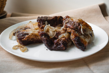 beef and onion baked in foil is on a white plate