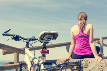 Obraz premium Female cyclist taking a rest and enjoying sea view. Living life.