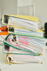 Close-up of table with stack of colorful folders full of files with attached adhesive notes in...