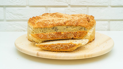 Bochenek chleba, dorodny, duży upieczony w domu. Chleb z ziarnami na drewnianej desce na białym tle