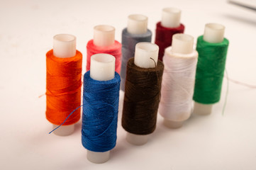 Several reels of multicolored sewing thread on a white background. Close up.