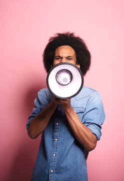 Young African man shouting through a megaphone in studio shot.