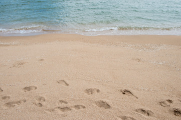 Fototapeta na wymiar Background of footprint on the beach with sea wave