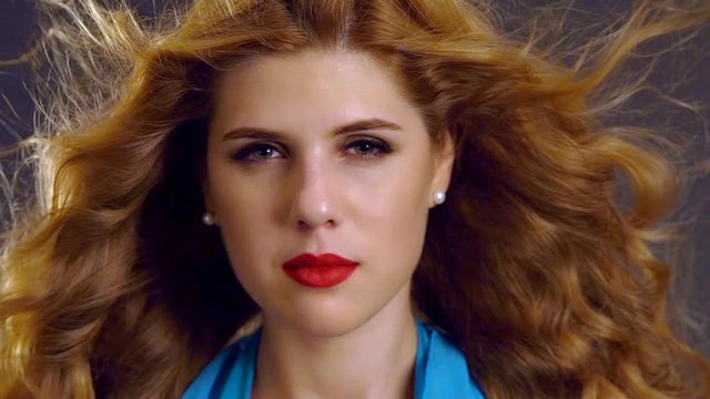 Slow motion of flying hair. Horizontal portrait of young woman with red lips and hypnosis look.