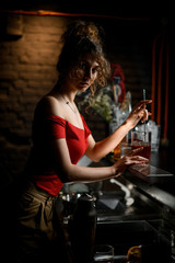 Fototapeta na wymiar lady barman stirring drink in cup with bar spoon