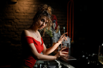 female barman stirring drink in cup with bar spoon