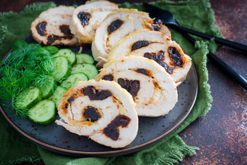 Chicken roll with prunes with fresh cucumbers and herbs, selective focus