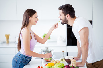 Obraz na płótnie Canvas Profile side photo of two people enjoy passionate bonding evening stay home quarantine dish woman feed salad her sweetheart man in house kitchen indoors