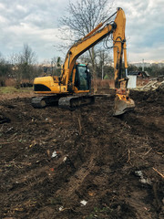 Excavator uprooting trees on land in countryside. Bulldozer clearing land from old trees, roots and branches with dirt and trash. Backhoe machinery. Yard work © sonyachny