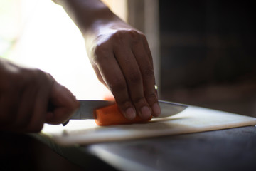 Woman cutting carrot with a knife on a chopping board in an Indian kitchen