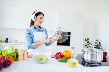 Portrait of her she nice attractive cheerful cheery funny funky housewife cooking dish culinary stay home listening music having fun quarantine in modern light white interior kitchen house