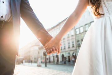 Obraz na płótnie Canvas Wedding couple holding hands on sunset background