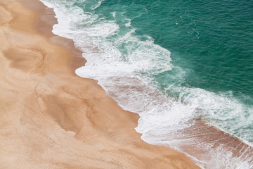 Aerial view of the sandy beach and the big turquoise waves of the Atlantic Ocean. Nazare, Portugal.