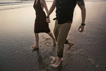 Lovely couple running together holding hand through the beach