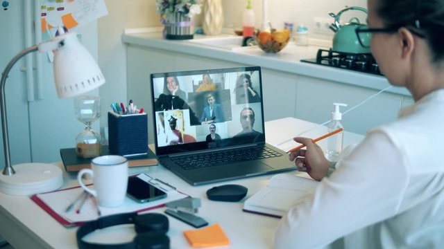 Woman talks to her colleagues via laptop while staying home.
