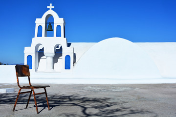 Traditional white and blue belfry with cross and bells of Greek orthodox church in Oia village, Santorini, Greece