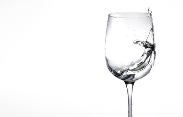 Water in a wine glass. Splash of liquid on a white background. Isolated object. Spray. Copy space for text. Selective focus.