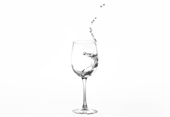 Water in a wine glass. Splash of liquid on a white background. Isolated object. Spray. Selective focus.