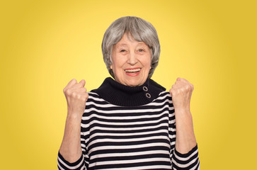 The portrait of a cheerful senior woman gesturing victory