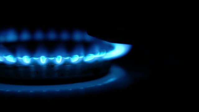 Turning on the cooktop gas cooker on black background. Kitchen burner turning on. Close up on the flame