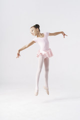 Delicate girl ballerina jumping on white background in studio. Kinds personality development concept.
