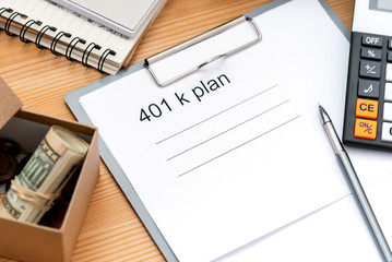 401 K plan list with folder, notepad and calculator on wood.