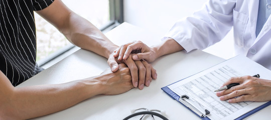 Doctor touching patient hand for encouragement and empathy