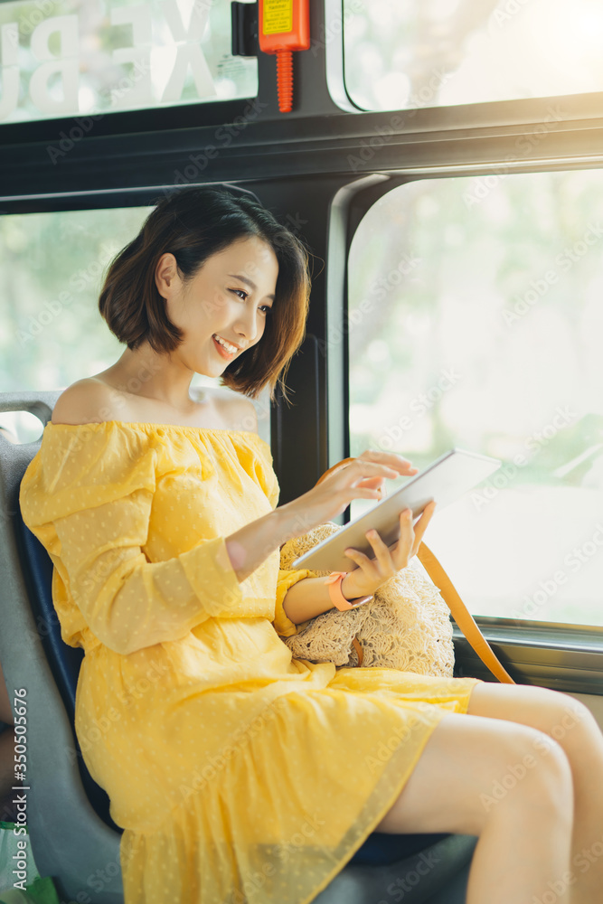 Wall mural beautiful woman using tablet when sitting on the bus.