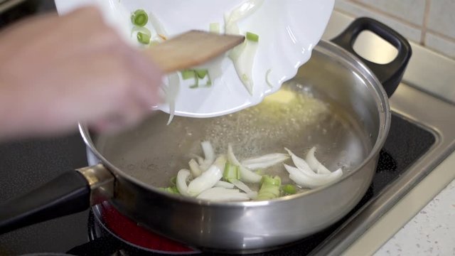 Pouring onions into a hot pan