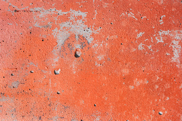 Textured surface of an old orange painted concrete wall.