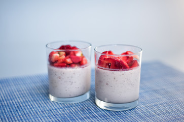 Layered strawberry homemade italian creamy dessert panna cotta with fresh berries in glass on blue background. Organic sweet. Side view of strawberry panna-cotta