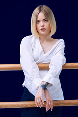 Portrait of a pretty blonde woman standing looking to the camera with crossed hands in white shirt 