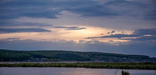 Evening landscape with lake, reeds and dramatic sky