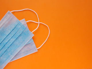 Two medical protective sterile blue masks on a orange background with copy space