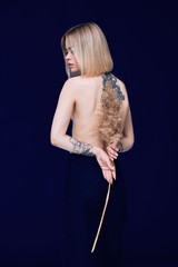 Fototapeta premium Portrait of a pretty blonde woman standing looking to the camera holding a wheat stalk 
