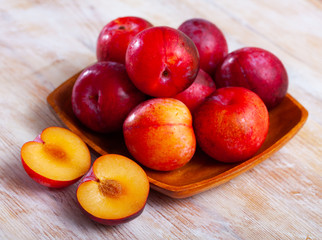 Ripe red plums in wooden bowl