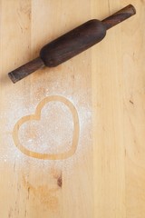 Heart prints and drawing with flour on the board with rolling pin. Rough wooden rectangular cutting...