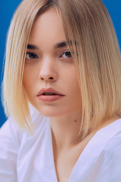 Cole up portrait of beautiful woman with nude make up on blue background looking in camera 