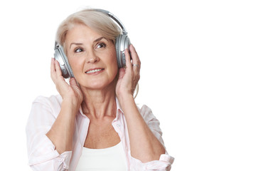 Naklejka premium Cheerful mature woman is listening to music in headphones
