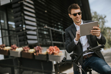 Young businessman on the ebike with digital tablet