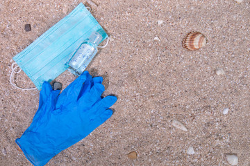 The concept of a background vacation trip with beach accessories and medical mask on a sand background at the time of the coronavirus pandemic. Top view with copy space.