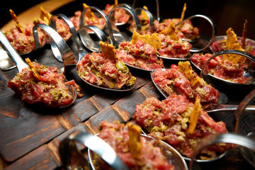 cold fish appetizers on a spoon, on a wooden black board
