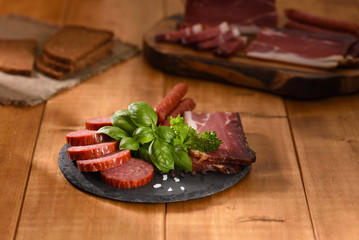 Ham and smoked sausage cutting on a slate plate. A snack in between.