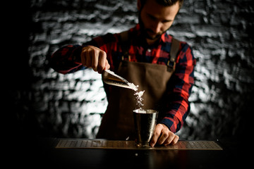 male bartender pours ice into metal glass