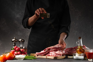 Cooking fresh pork ribs. For roasting and cooking. Chef sprinkles with seasoning for roasting. Classic American dish